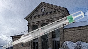 thermomètre en gros plan devant la façade d'une mairie.