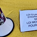 mégaphone et pancarte "loi d'urgence agricole ? Non ! Loi mortifère pour tous"